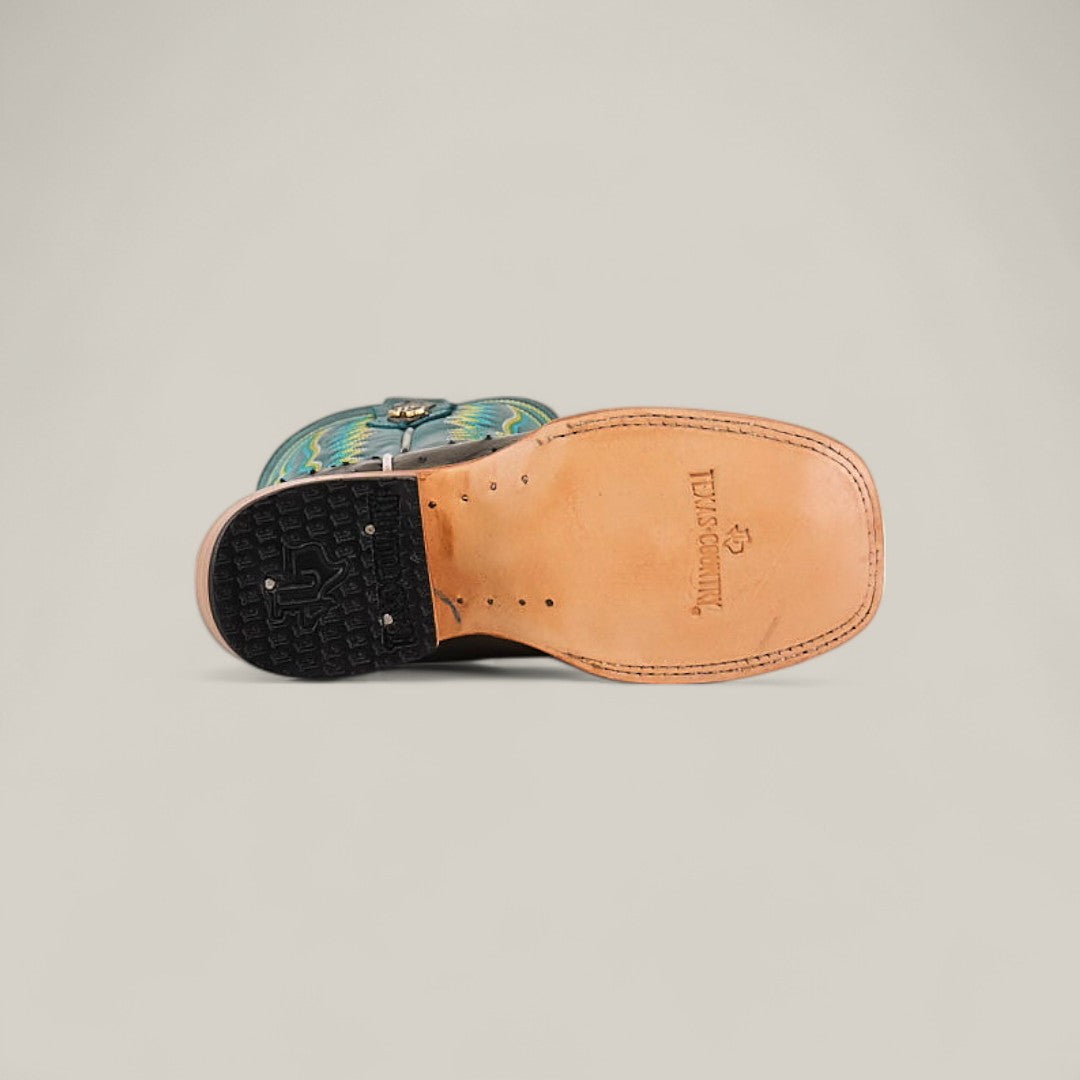 The Exotic Full Quilt Ostrich Gray - Square Toe - Kids Boots feature a light tan ostrich leather sole with stitched edges, black rubber heel, and a blue and green patterned upper that showcases western style.
