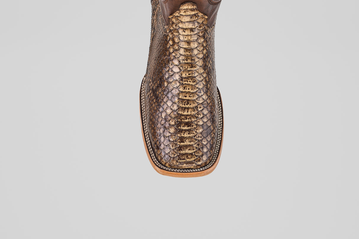 A close-up of the Tanner – Dune – Square Toe boot showcases its shiny python leather finish and detailed stitching on the toe, set against a plain white background—ideal for fans of western-inspired boots.