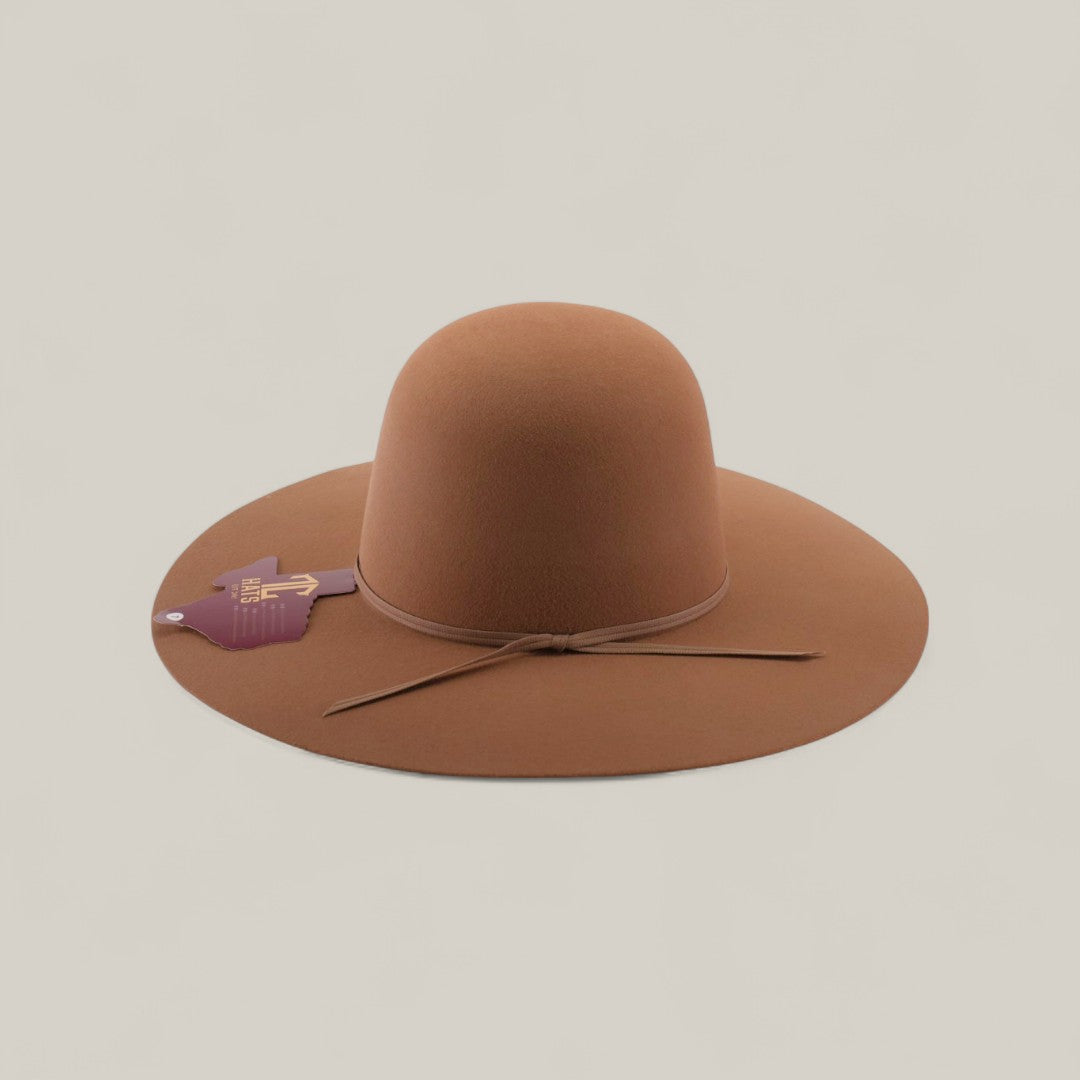 The 4X - Fawn - TC Hats is a wide-brimmed brown Western hat with a shapeable crown and thin string around the base, displayed on a light beige background. A purple hand-shaped tag is attached to the hat.