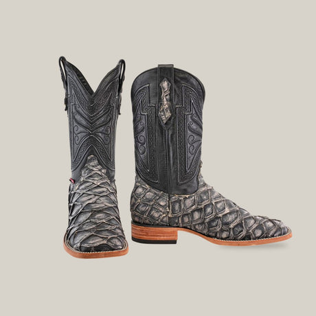 A pair of black cowboy boots with a textured, scale-like pattern and brown soles, displayed against a plain light background.