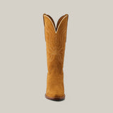 The Miranda Suede boot in gold leather stands upright, showcasing its snip toe, decorative white stitching, tan color, and slightly curved top edge against a plain background.
