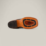 The image reveals the sole of an Exotic Caiman Belly Tail shoe, Gray with a Square Toe, featuring a unique Western-style pattern. The textured grooves, stylized logo initials, and contrasting tan and black colors highlight the refined craftsmanship typical of exotic leather designs.