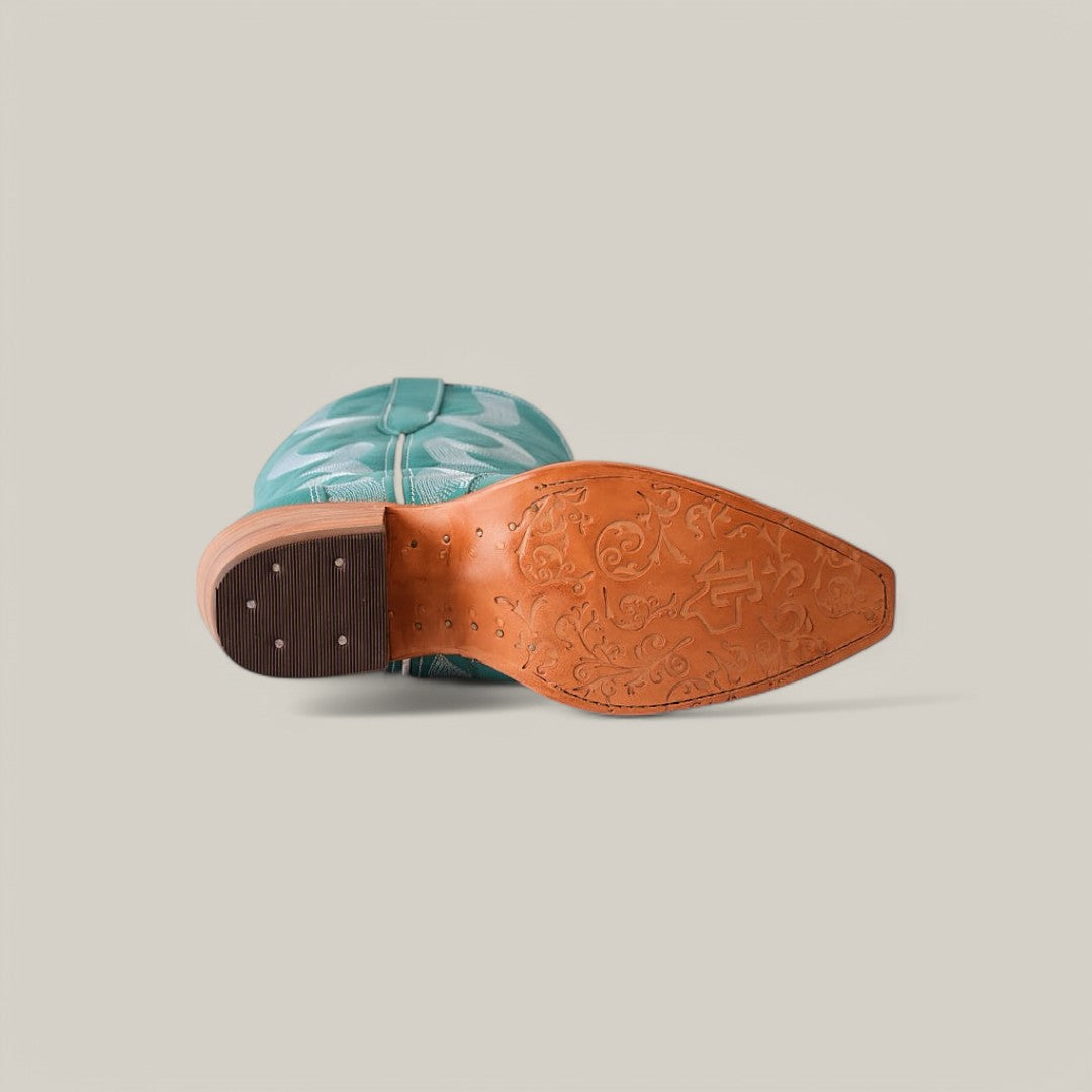 The image features the sole of an Olimpia Green Teel - Tall Shaft - Snip Toe cowboy boot with intricate patterns on the tan base. Tilted on its side, it showcases a turquoise upper adorned with decorative stitching against a plain, neutral background.