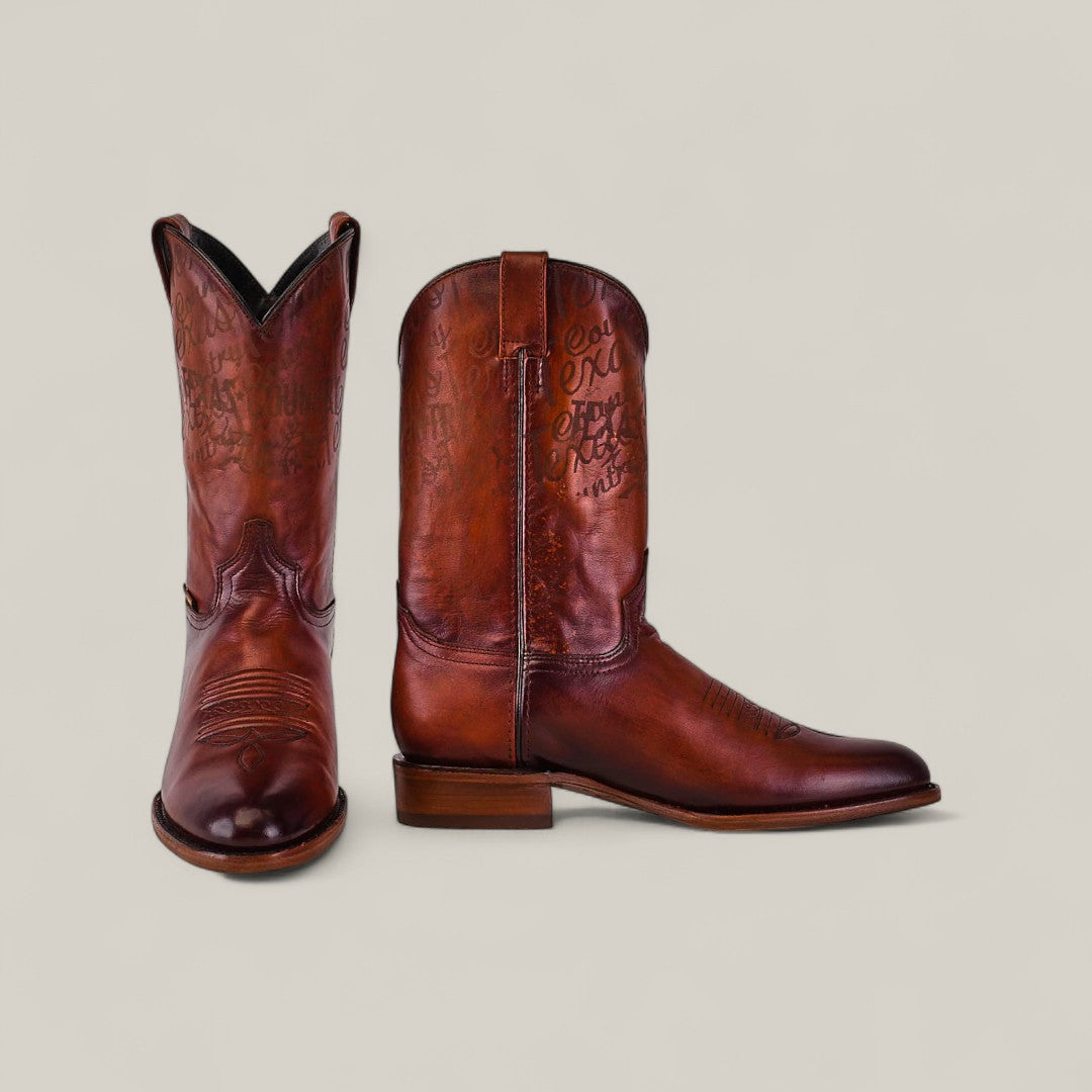 The Wyatt - Camel - Roper Toe boots in brown cowhide feature decorative stitching and engravings, displayed from the front and side against a plain light background to highlight their quality craftsmanship.