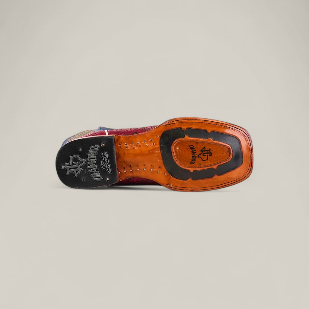 The underside of the Exotic Python - Ruby / Blue - Square Toe boot features decorative stitching, branded logos, and a black rubber heel cap from the Platinum Collection, set against a plain light background.