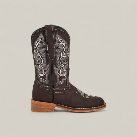 The Amara Suede Oxford - Square Toe Kids Boots are shown in profile, featuring dark brown suede, white embroidery, silver studs on the shaft, pull straps, and a light brown stacked heel and sole against a neutral background.