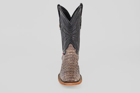 The Exotic Caiman Horn Back - Serpentine - Square Toe boot is shown from the front, displaying a textured reptile-like lower, dark stitched shaft, and light brown sole—a classic western look against a plain background.