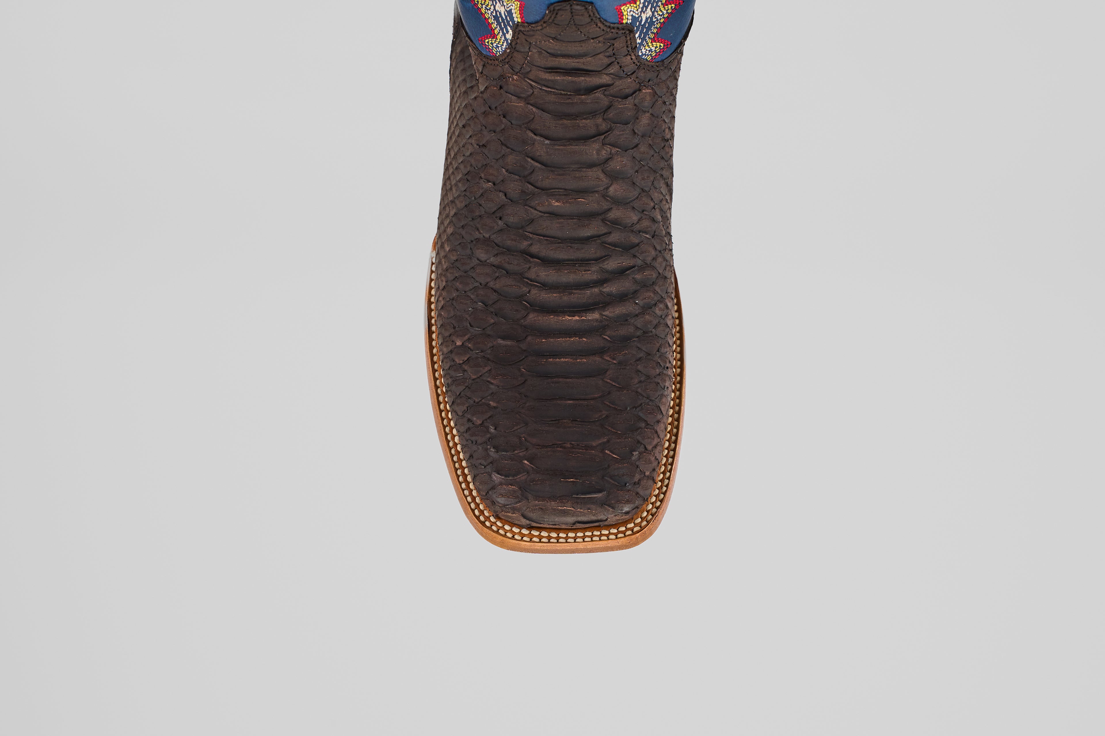 A close-up top view of the Morgan - Matte Brown - Square Toe men’s boot, showing its textured matte brown finish, detailed stitched edge, and a hint of colorful design near the upper.