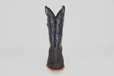 The Tanner – Matte Black – Roper Toe boot stands upright on a light brown sole, featuring a scaly texture and stitched star emblem on the shaft, showcasing western style against a clean white background.