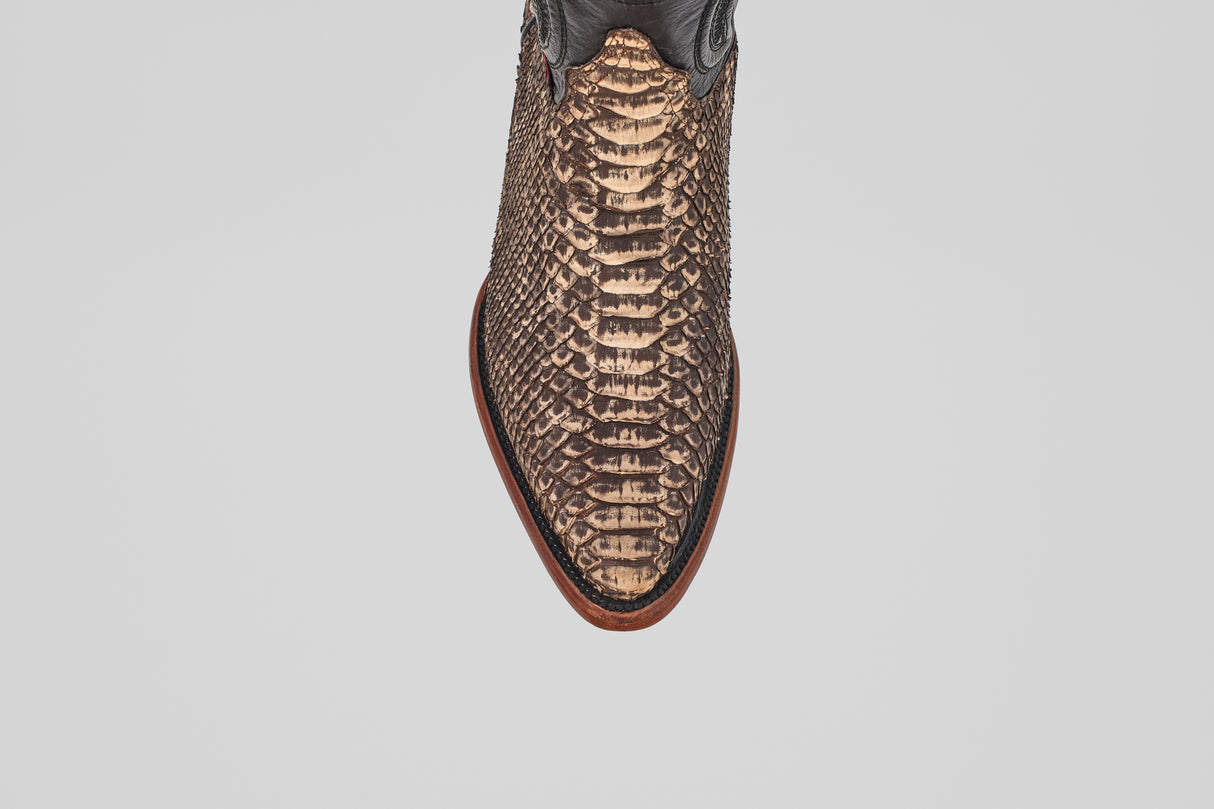 Close-up, top-down view of the Tanner – Rustic Bone – Snip Toe boot, featuring a pointed toe, brown snakeskin-patterned leather, and a reddish-brown sole—these western-inspired boots stand out on a white background.