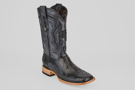 The Tanner - Black - Square Toe cowboy boot features a textured lower section, decorative stitching on the upper shaft, and a light brown wooden heel and sole, all set against a plain white background.