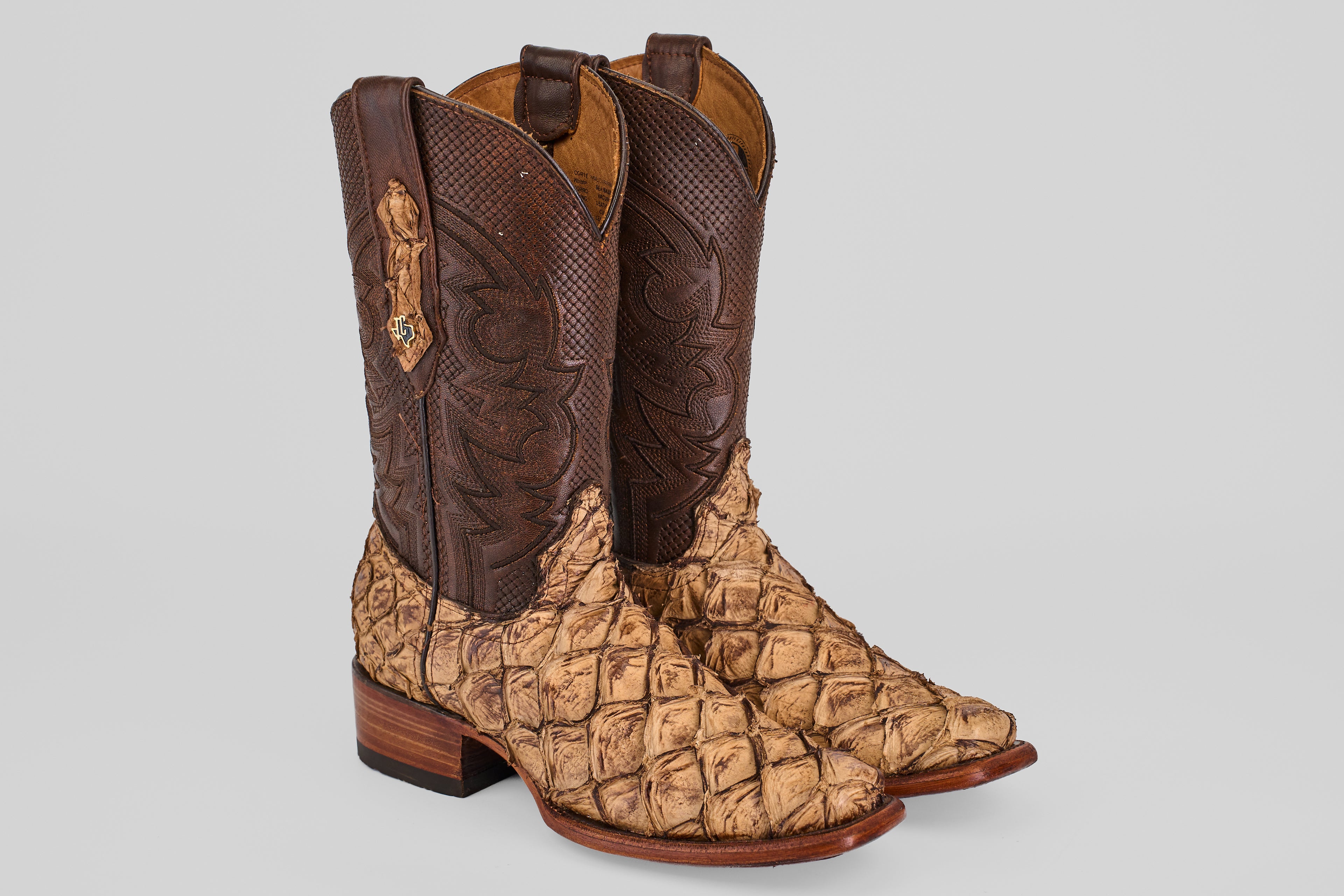 The Conor - Matte Orix - Narrow Square Toe cowboy boots feature dark brown leather shafts and textured tan Pirarucu leather on the foot, displayed against a plain light gray background.