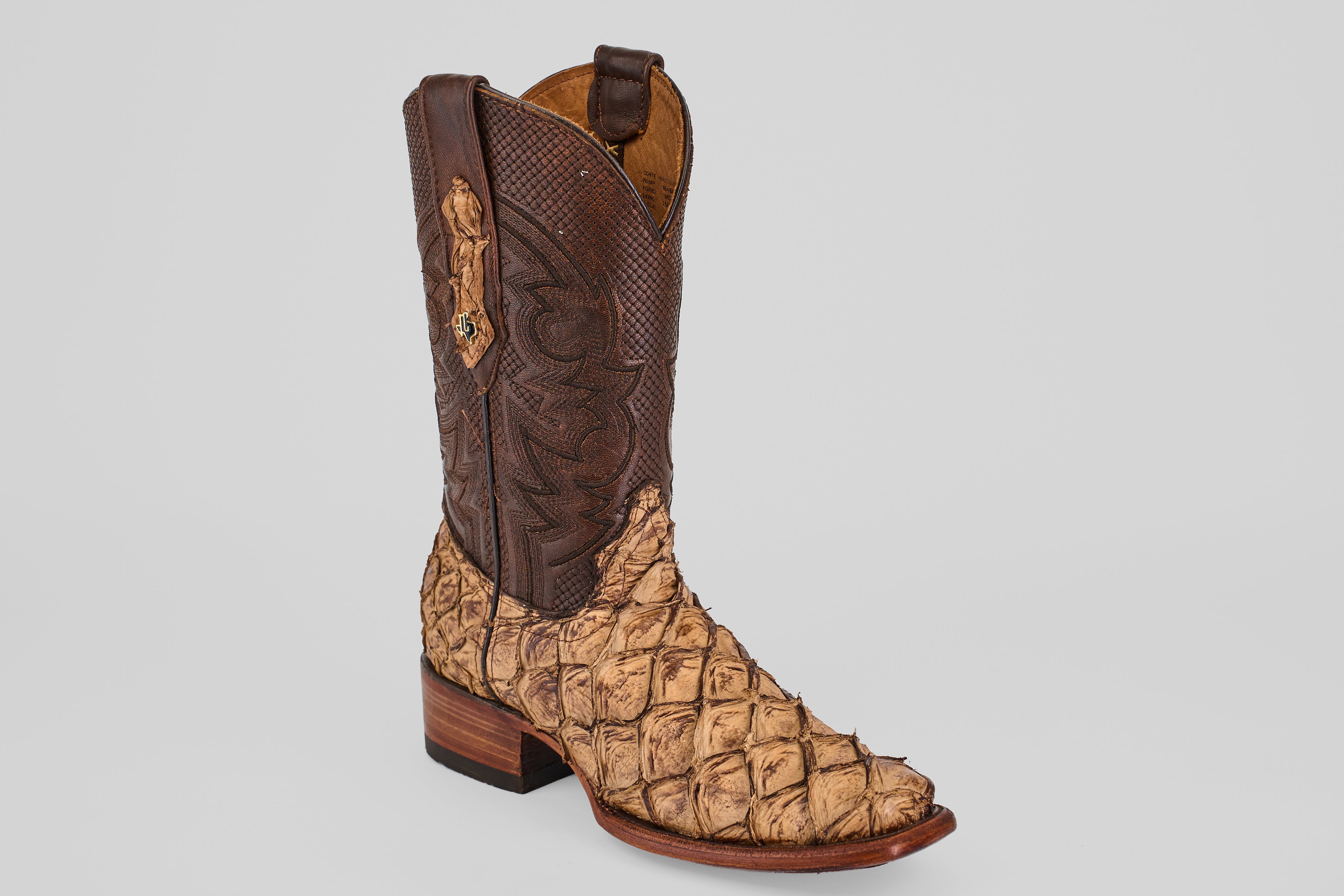 The Conor - Matte Orix - Narrow Square Toe is a cowboy boot featuring a brown, textured leather shaft and a tan, scaled Pirarucu leather foot with a low stacked heel and narrow square toe.
