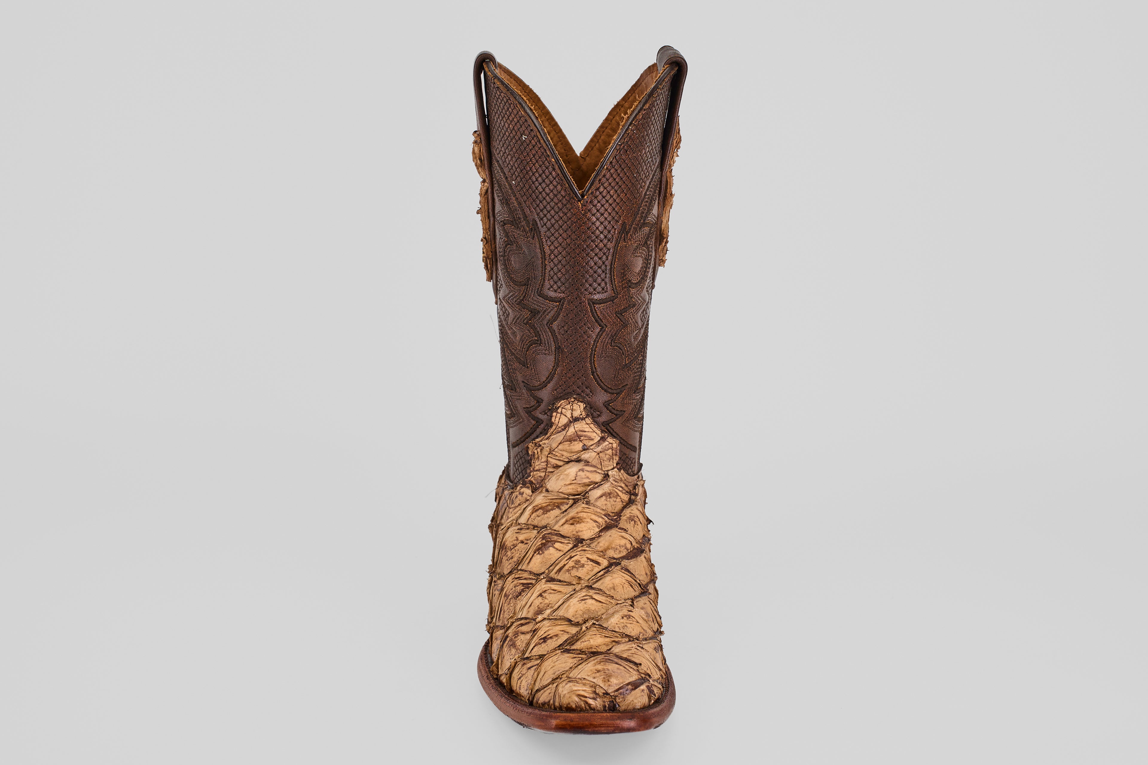 The Conor - Matte Orix - Narrow Square Toe features a single cowboy boot with textured tan Pirarucu leather in a matte finish and a dark brown, intricately stitched upper, shown on a plain light gray background.