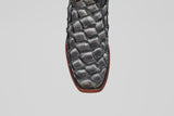 Close-up of the Conor - Newspaper cowboy boot toe in black fish leather with a narrow square toe and brown sole, set against a plain white background.
