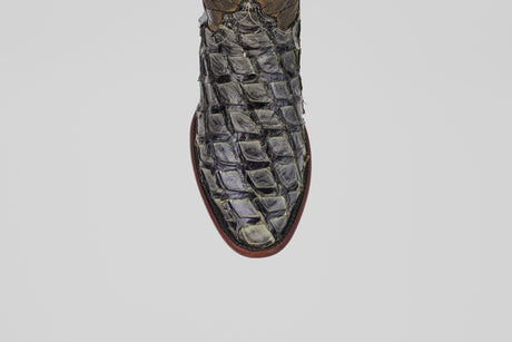 Close-up of the Conor - Charcoal - Roper Toe boot's textured, dark charcoal toe with a square pattern, possibly crafted from exotic fish leather, shown against a plain light gray background.