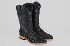 The Conor - Matte Black - Roper Toe boots feature textured pirarucu fish leather, high-calf design, decorative stitching, and light brown wooden heels, all showcased against a plain gray background.