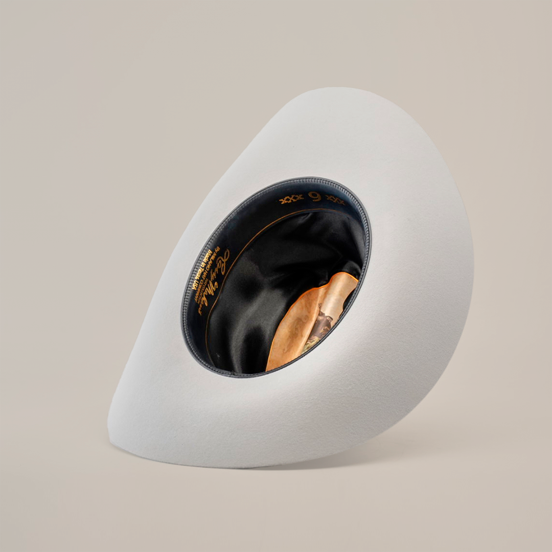 The 6X Real Platinum hat, featuring a stylish wide asymmetric brim and black interior lining, is displayed upside down on a white background, showcasing its unique craftsmanship.